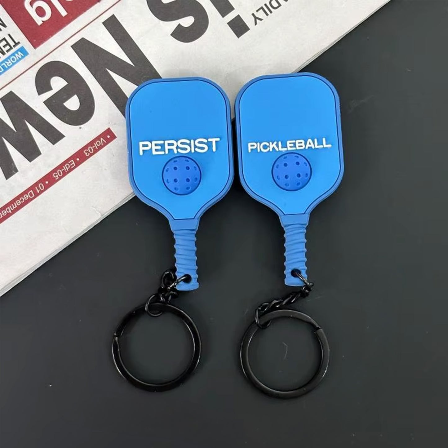 Vue recto et verso d'un porte-clés raquette de pickleball bleu ciel en silicone.