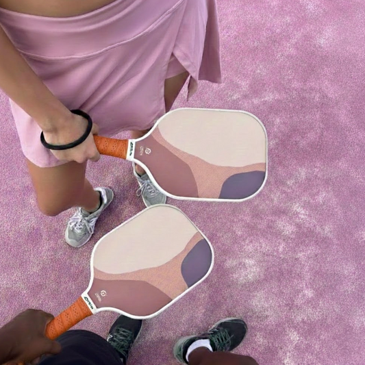 Raquette Blush de Smashline portée par deux joueurs sur un terrain de pickleball moderne.