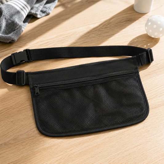 Pochette ceinture de sport noire réglable en maille filet vide pour l'entraînement de pickleball, posée sur une table en bois.
