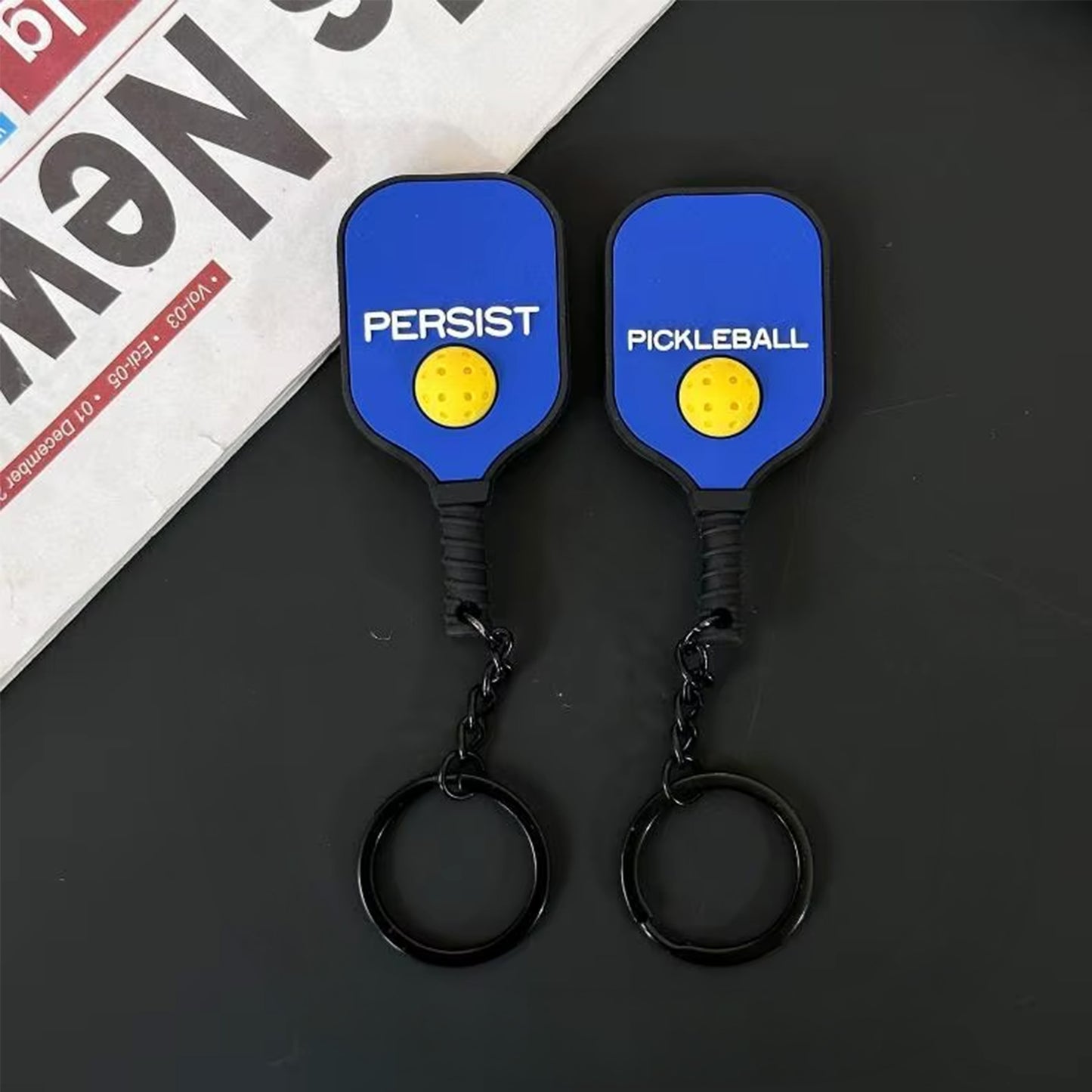 Porte-clés en silicone bleu roi pour sac de pickleball, présenté de face et de dos.