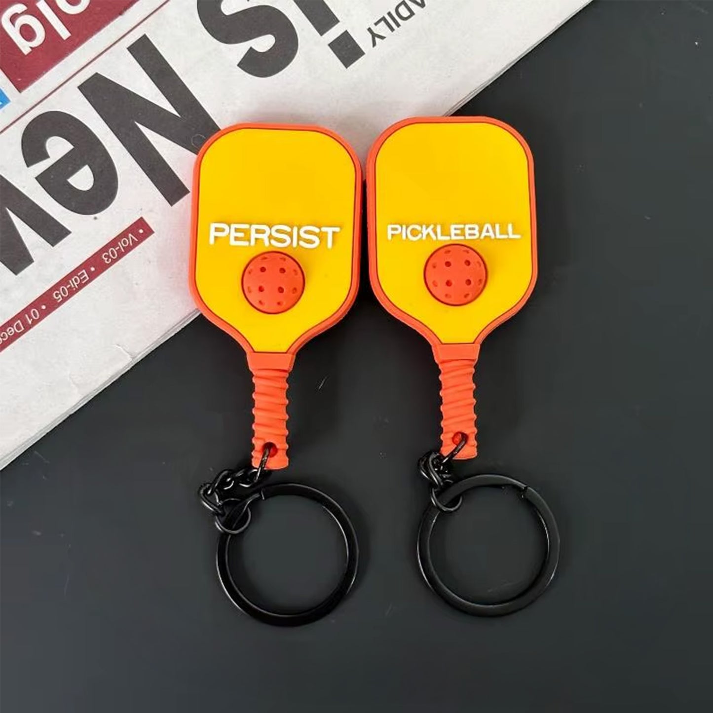 Vue recto verso d'un porte-clés raquette de pickleball jaune et orange.