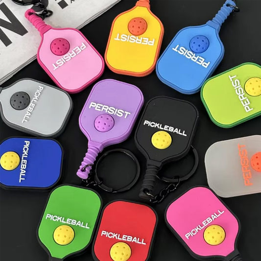 Variations colorées de porte-clés en silicone en forme de raquettes de pickleball avec les inscriptions Pickleball et Persist.