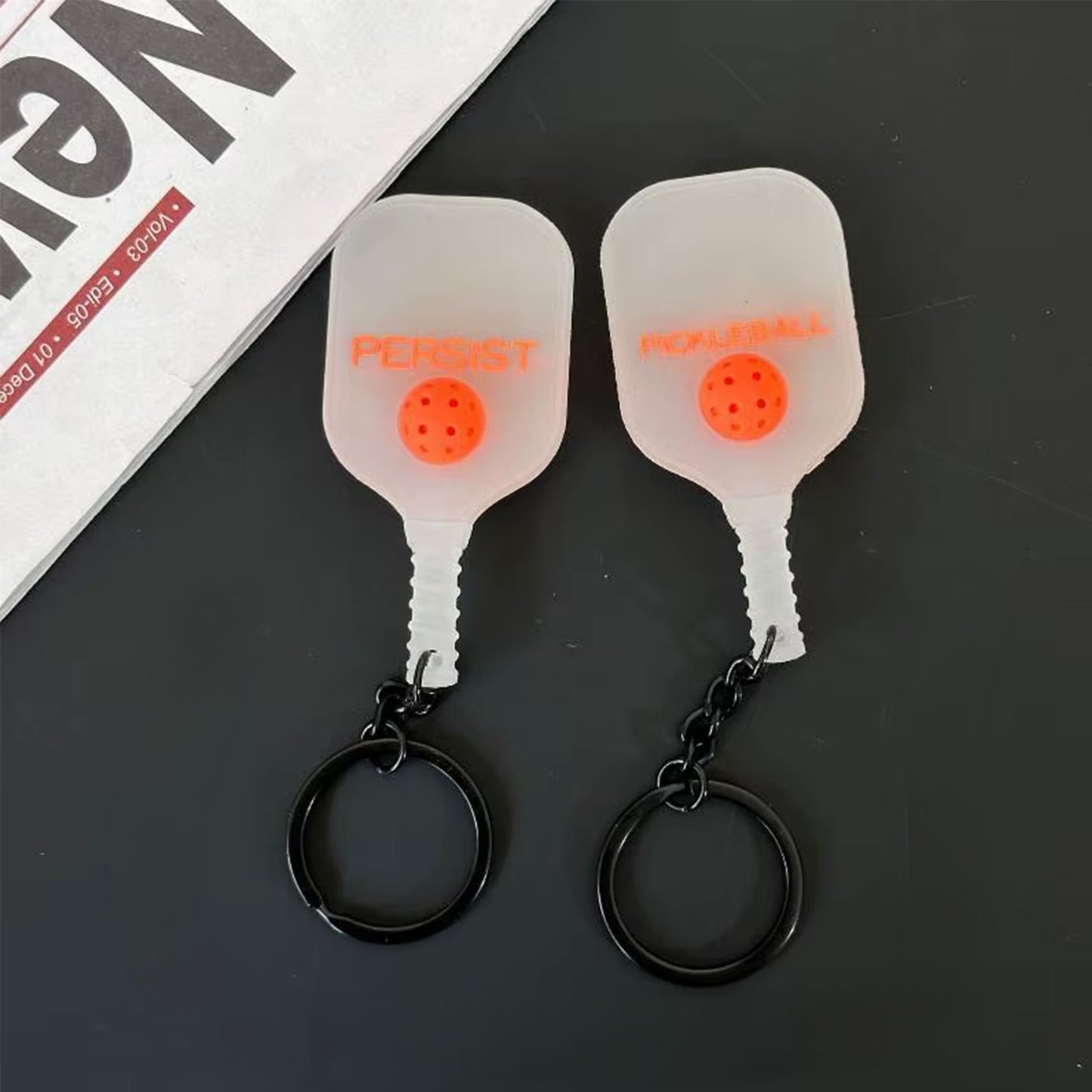 Porte-clés en silicone transparent givré avec lettrage orange, vu des deux côtés.
