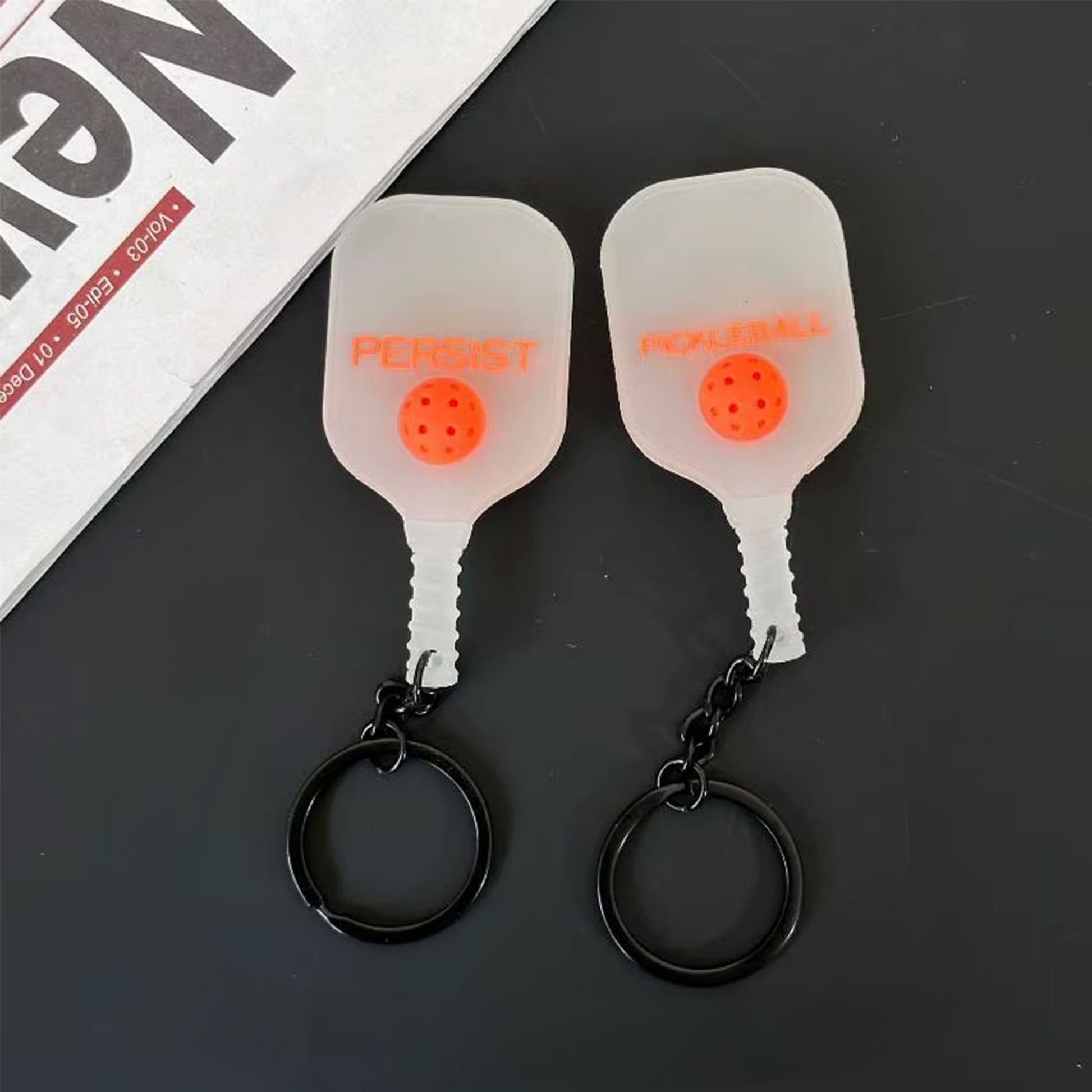 Porte-clés en silicone transparent givré avec lettrage orange, vu des deux côtés.