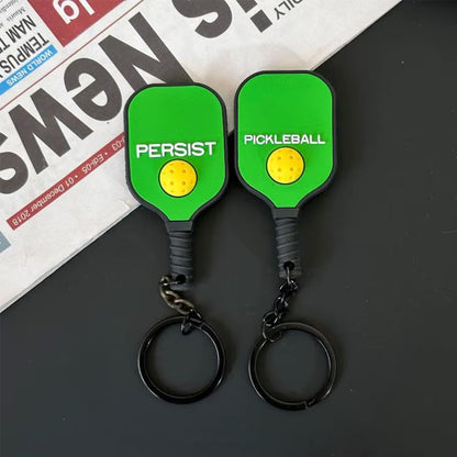 Vue recto et verso d'un porte-clés en caoutchouc vert foncé en forme de raquette.