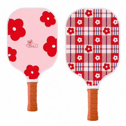 Vue des deux faces de la raquette en carbone Bloom Pink, l'une rose à fleurs rouges et l'autre à motif tartan écossais fleuri.