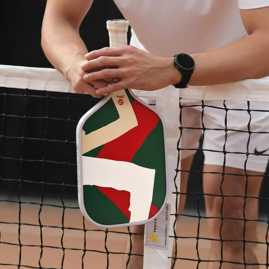Un gros plan de la raquette géométrique Fold de Smashline tenue par un homme sur un terrain de pickleball