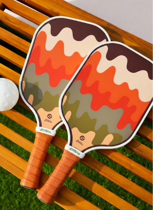 Raquette Melt Smashline posée à côté de balles de pickleball sur un terrain extérieur.