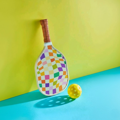 Raquette à damier psychédélique Mosaic tenant sur un mur avec une balle jaune.
