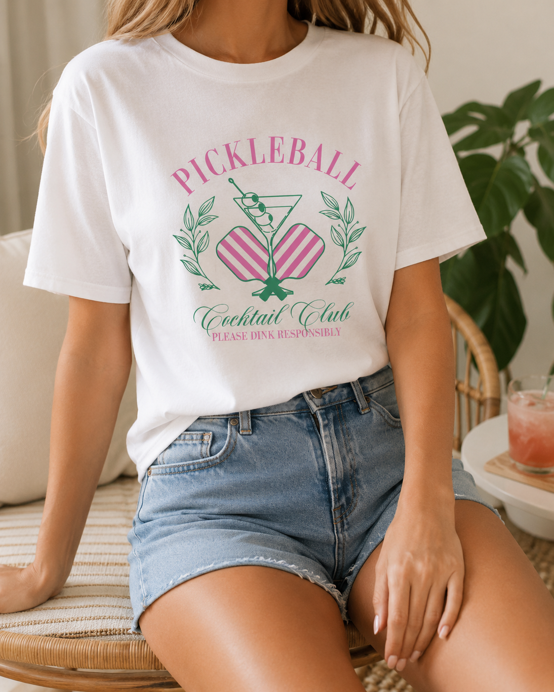 Jeune femme portant le t-shirt blanc Pickleball Cocktail Club avec un short en jean, style décontracté.